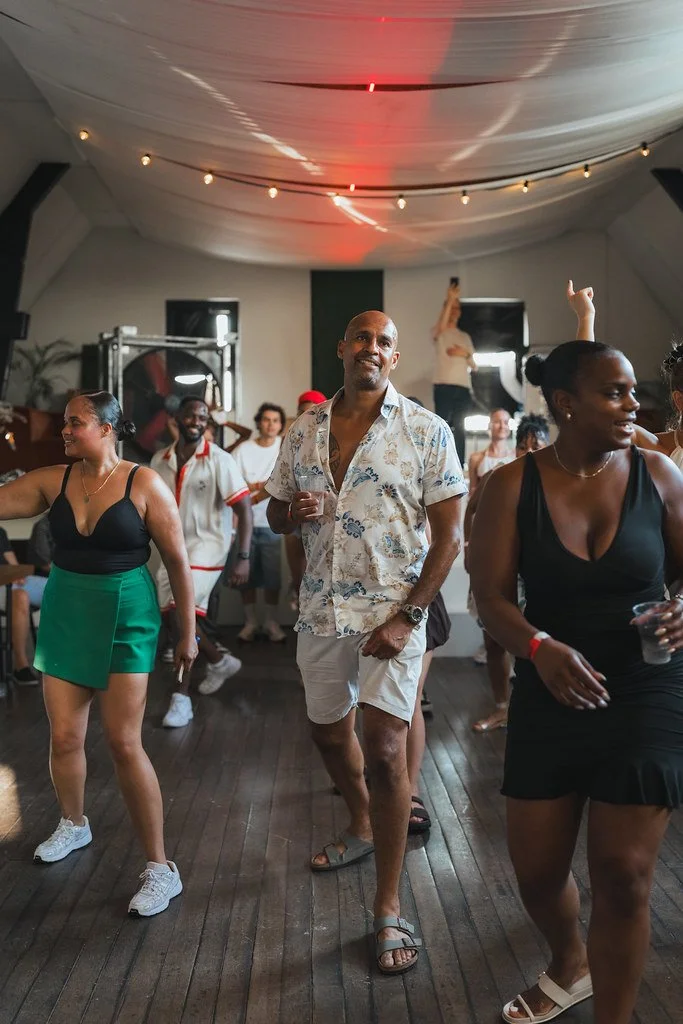 Gasten dansen met een drankje in de hand onder de lichtslingers