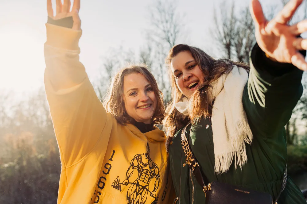 Twee wandelaars zwaaien lachend naar de camera